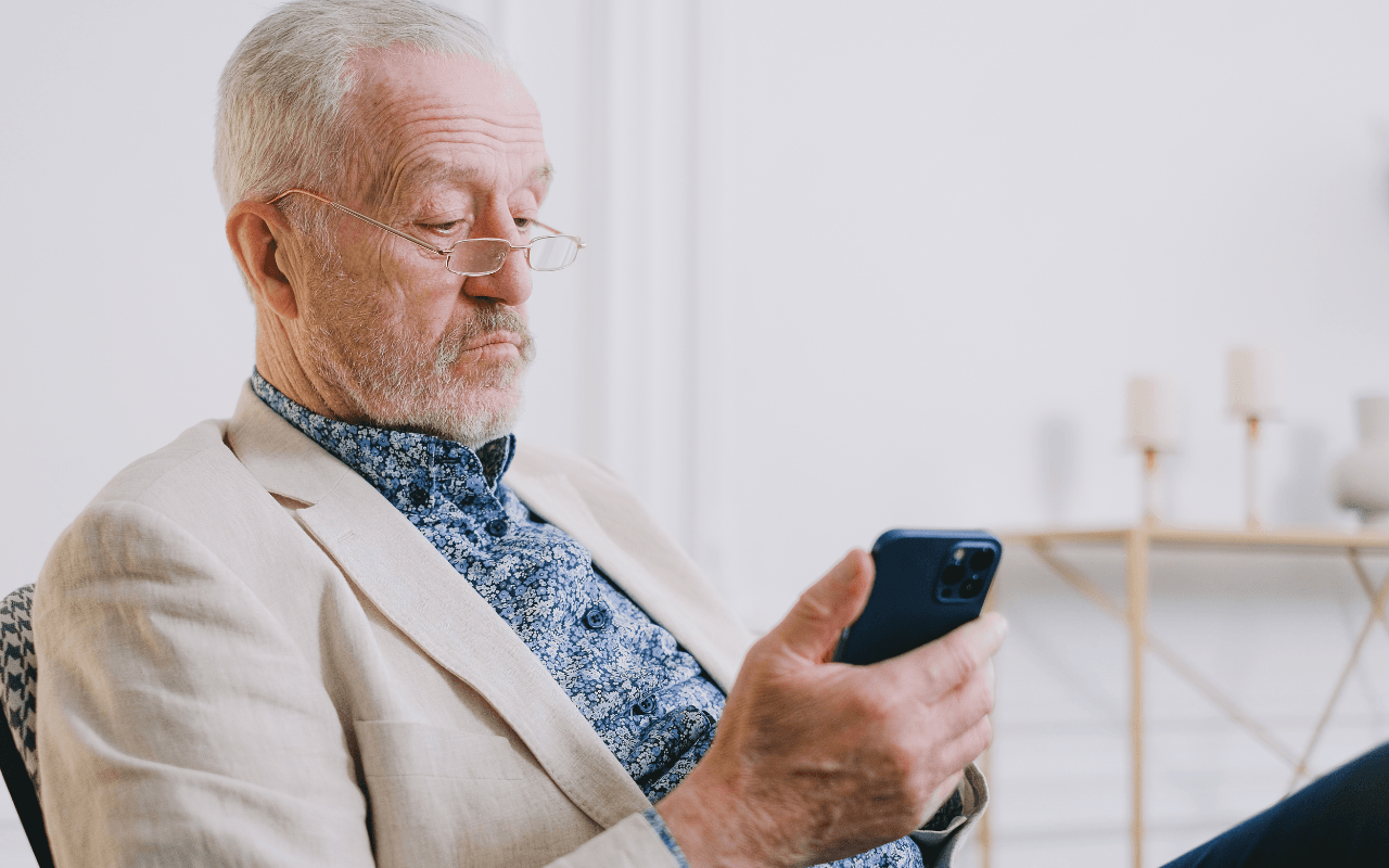 Homem idoso a usar um telefone, simbolizando comunicação